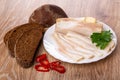 Salted pork lard, parsley in plate, bread, pieces of chili pepper on table