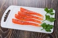 Slices of salted salmon, parsley on plastic cutting board