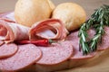 Slices of sausage and bacon on a cutting board with bread rolls, Royalty Free Stock Photo