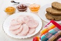 Slices of sausage, bread, spoon, bowls with sauces and napkin