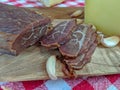 Slices of smoked beef meat, garlic cloves, cheese and bread as a traditional and delicious meal on retro picnic style red colorful