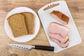 Slices of smoked gammon on cutting board, rye bread Royalty Free Stock Photo