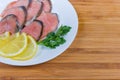 Slices of smoked pink salmon, lemon and parsley on dish