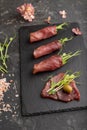 Slices of smoked salted meat with green pea microgreen on black. Side view, close up