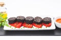 Slices of Spanish black pudding on piquillo peppers in white plate on white background. Spanish tapas Royalty Free Stock Photo