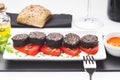 Slices of Spanish black pudding on piquillo peppers in white plate on white background. Spanish tapas Royalty Free Stock Photo