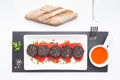 Slices of Spanish black pudding on piquillo peppers in white plate on white background. Spanish tapas Royalty Free Stock Photo