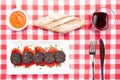 Slices of Spanish black pudding on piquillo peppers in white plate on a red checkered tablecloth . Spanish tapas Royalty Free Stock Photo