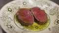 Slices of steak being sprinkled with salt placed on plate