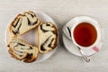 Slices of sweet bun with poppy in plate, cup of tea, spoon on saucer on wooden table. Royalty Free Stock Photo