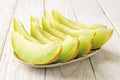 Slices of sweet juicy galia melon with green pulp on a plate over white wood table. Ingredient for fruit desserts. Vegetarian, raw Royalty Free Stock Photo