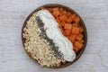 Slices of sweet papaya with oat flakes, chia seeds and white yogurt in coconut bowl on white wooden background, close up Royalty Free Stock Photo