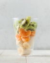 Slices of tangerine, banana and kiwi in a clear glass. Fruit salad, takeaway food.