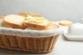 Slices of tasty fresh bread with butter in wicker basket on marble table Royalty Free Stock Photo