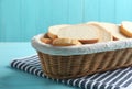 Slices of tasty fresh bread in  basket on light blue wooden table, closeup Royalty Free Stock Photo