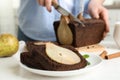 Slices of tasty pear bread and view of woman with knife on background Royalty Free Stock Photo