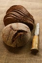 Slices and loaf of rye bread and finnish knife puukko on burlap