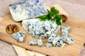 Slices and triangles of Danish Blue dorblue cheese with mold on wooden board background.