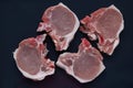 Slices of uncooked pork steak on black background. Raw pork fat, bloody meat on dark pan.