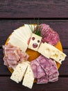 Slices of various cheeses, sausages and meat are arranged on a plate. The art of making a slice of cheese with holes looks like a Royalty Free Stock Photo