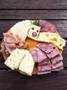 Slices of various cheeses, sausages and meat are arranged on a plate. The art of making a slice of cheese with holes looks like a Royalty Free Stock Photo