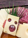 Slices of various cheeses, sausages and meat are arranged on a plate. The art of making a slice of cheese with holes looks like a Royalty Free Stock Photo