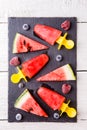 Slices of watermelon, fruit ice, frozen blueberries, raspberries on black board Royalty Free Stock Photo