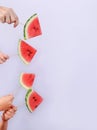 slices of watermelon are held by two pairs of hands