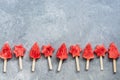 Slices of watermelon on a stick in the shape of a Christmas tree and stars on a gray background. Popsicles in a row. Top view,