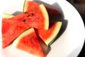 Slices of watermelon on a white plate with sunlignt in the morning.