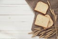 Slices of white bread and wheat ears on sacking on white boards. Royalty Free Stock Photo