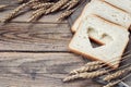 Slices of white bread and wheat ears on sacking on a wooden table. Royalty Free Stock Photo