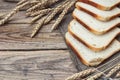 Slices of white bread and wheat ears on sacking on a wooden tabl Royalty Free Stock Photo