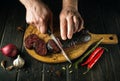 Slicing blood sausage by the hands of cook on a cutting board. Cooking national dish on the kitchen table Royalty Free Stock Photo