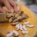 Slicing brown button mushroom with a santoku chef knife. Royalty Free Stock Photo