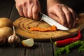 Slicing carrots on a wooden board for cooking. Professional chef hands with a knife while working on the kitchen table Royalty Free Stock Photo