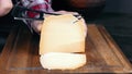 Slicing cheese. A man cuts cheese on a cutting board.Hard cheese varieties. Parmesan cheese.
