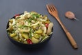 Slicing fermented green tomatoes and cucumbers with onions and pickled peppers in a black cup Royalty Free Stock Photo