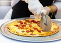 Slicing Fresh Made Italian Pizza, Closeup hand of chef cutting pizza in kitchen Royalty Free Stock Photo