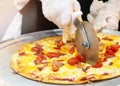 Slicing Fresh Made Italian Pizza, Closeup hand of chef cutting pizza in kitchen Royalty Free Stock Photo