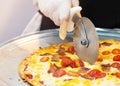 Slicing Fresh Made Italian Pizza, Closeup hand of chef cutting pizza in kitchen Royalty Free Stock Photo