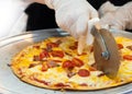 Slicing Fresh Made Italian Pizza, Closeup hand of chef cutting pizza in kitchen Royalty Free Stock Photo