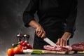 Slicing fresh meat, pork ribs on a background of fresh vegetables and a gray wall with space Royalty Free Stock Photo