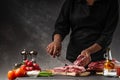 Slicing fresh meat, pork ribs on a background of fresh vegetables and a gray wall with space Royalty Free Stock Photo