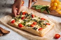 Hand slicing italian bread focaccia with spinach