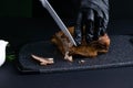 Slicing juicy beef steak by knife in chef hands closeup. Food cooking concept. Dark black background