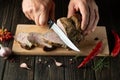 Slicing juicy beef steak with a knife in the hands of a chef close-up. The concept of cooking. Dark background for advertising or