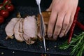 Slicing juicy beef steak by knife in women hands closeup. Food cooking concept. Dark black background