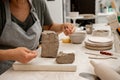 Slicing off a chunk of clay from a large block using a sharp wire clay cutter. Using a wire cutter to cut off a piece of