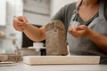 Slicing off a chunk of clay from a large block using a sharp wire clay cutter. Using a wire cutter to cut off a piece of